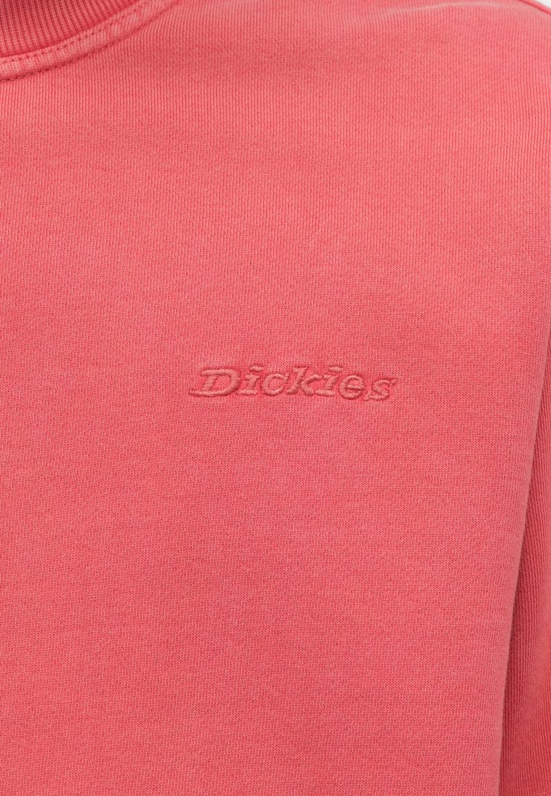 Felpa rosa con scollo arrotondato. Presenta il logo "Dickies" tono su tono ricamato con filo coordinato. Realizzata in tessuto morbido ed elastico.