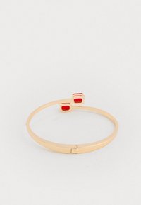 Zlatý náramok v tvare bangles s dvoma obdĺžnikovými červenými akcentmi. Hladký povrch s elegantným otvoreným dizajnom a bezpečným uzáverom.