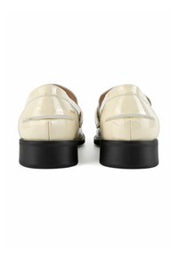 Beige patent leather shoes with a black block heel. Double strap design with small stitching details on the uppers. Smooth, glossy finish.