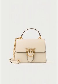 Beige läderhandväska med övre handtag, guldkedjestrap och guldfärgat fågelformat spänne på framklappen.