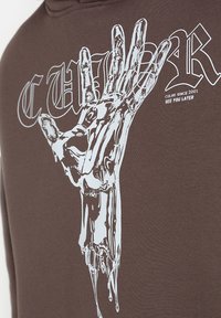 Brązowa bluza z kapturem z graficznym wzorem przedstawiającym szkieletową dłoń na białym tle, z tekstem "CUL8R SINCE 2001 SEE YOU LATER" w wyraźnym, pogrubionym foncie.