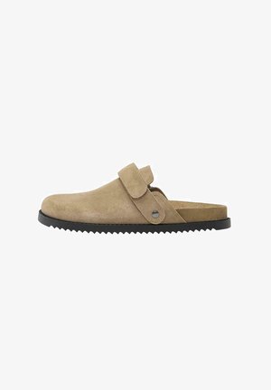 Beige velúr klump, kerek orral, állítható pánttal és textúrált fekete gumitalppal. Minimalista dizájnnal és biztonságos illeszkedéssel rendelkezik.