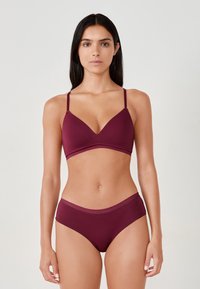 Bralet w kolorze maroon z cienkimi regulowanymi ramiączkami, dekoltem w kształcie litery V oraz pasującymi, wysokimi majtkami o miękkiej teksturze i kontrastowym wykończeniu.