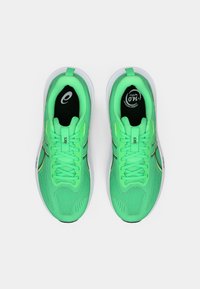 Zapatillas deportivas de color verde brillante con una parte superior de malla texturizada, logo circular en la lengüeta y suela de goma blanca. Presentan cordones planos y talón reforzado.