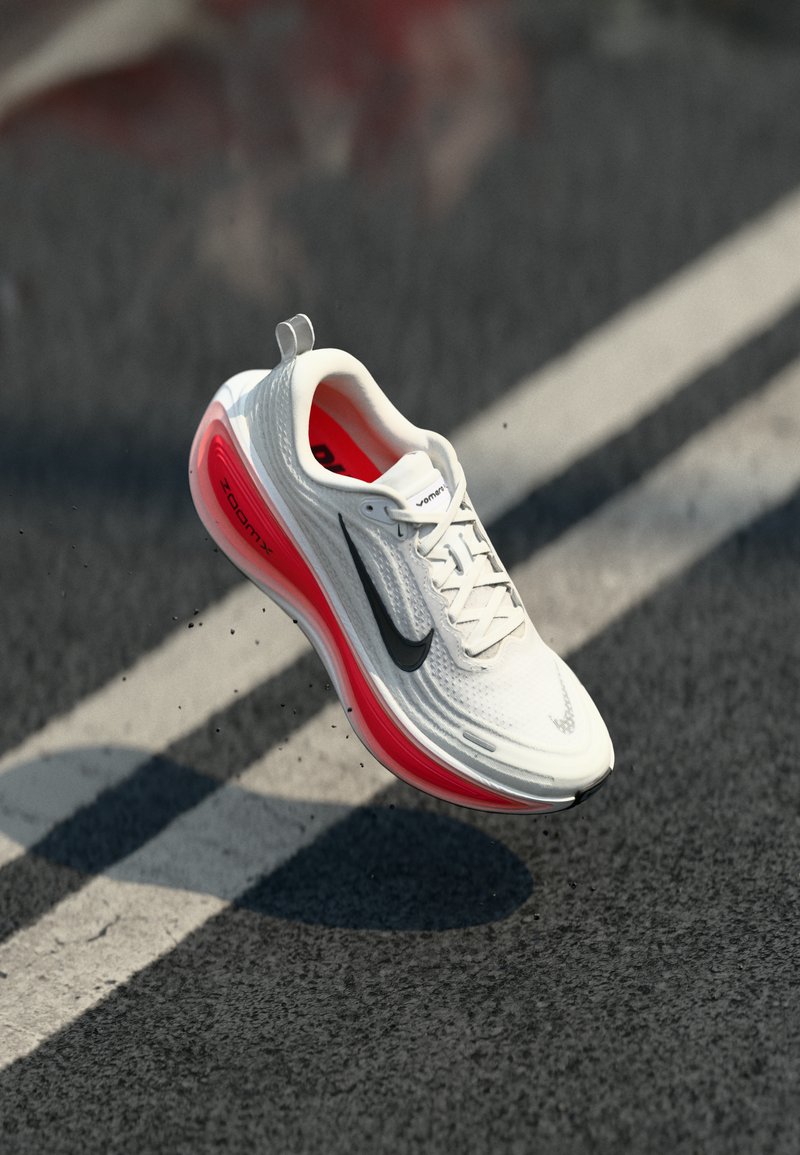 Chaussure de sport blanche avec un dessus texturé, logo Nike noir et amorti Zoom Air rouge sur la semelle, avec des lacets et une languette.