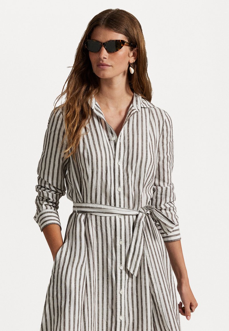Vestido de lino a rayas en blanco y gris, con cierre de botones en el frente, mangas largas, cintura ajustada y bolsillos laterales.