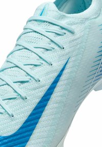 Light blue athletic shoe with textured fabric upper, featuring a blue swoosh and lace closure. Notable details include fine knit and patterned accents.