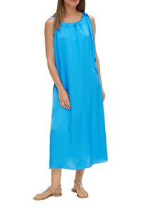 Leichtes, ärmelloses blaues Kleid aus leichtem Stoff; runder Ausschnitt mit Raffung; knielanger Saum; Modell trägt flache Sandalen.