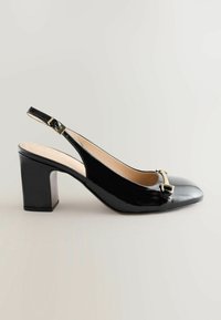 Musta lakattu slingback-korkokenkä, jossa on neliönmuotoinen kärki ja kultainen soljetta yksityiskohtana, vaaleaa taustaa vasten, esittelee kiiltävän pinnan.