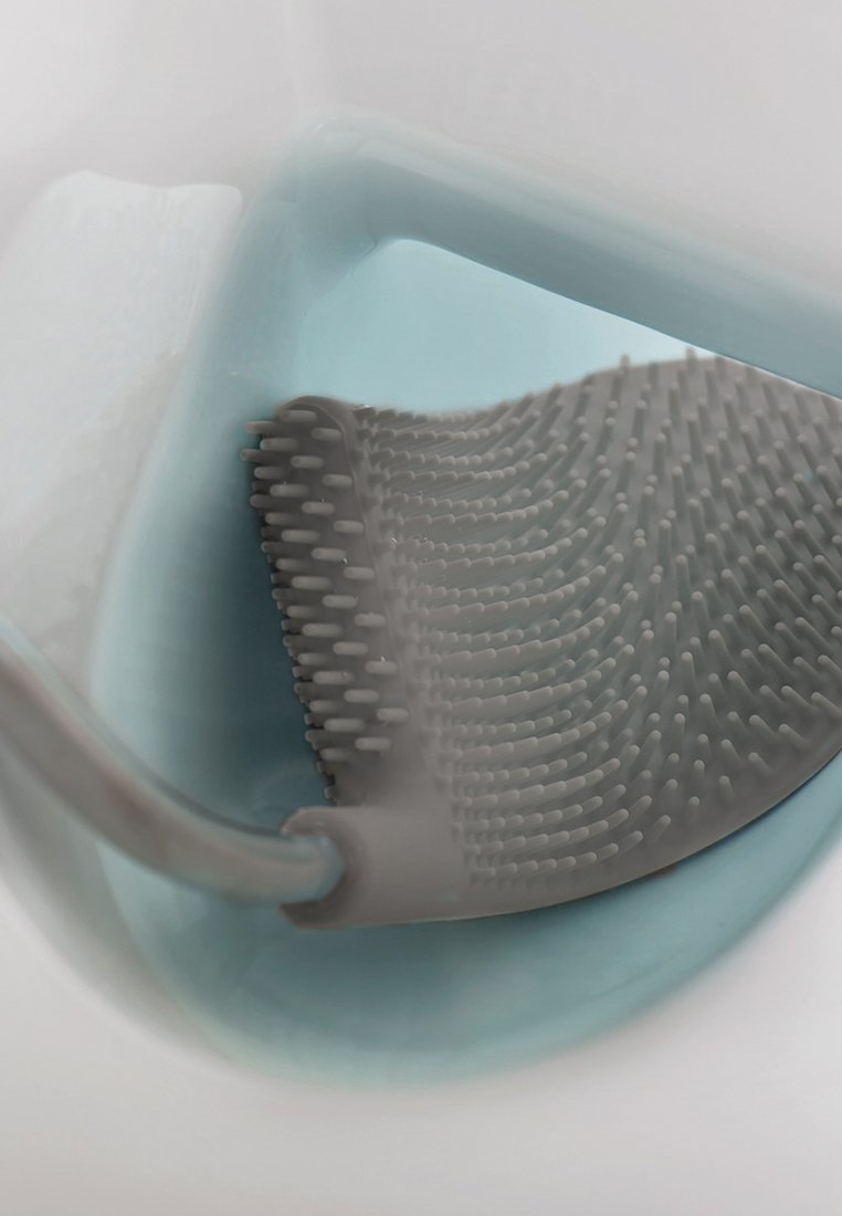 Silikon-Toilettenbürste mit gebogenem Griff. Die Borsten sind dicht angeordnet und sie befindet sich in hellblauem Wasser in einer weißen Toilettenschüssel.