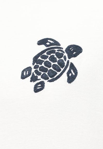 Σκούρα μπλε κεντημένη θαλάσσια χελώνα με διακοσμητικό κέλυφος σε λευκό υφασμάτινο φόντο.