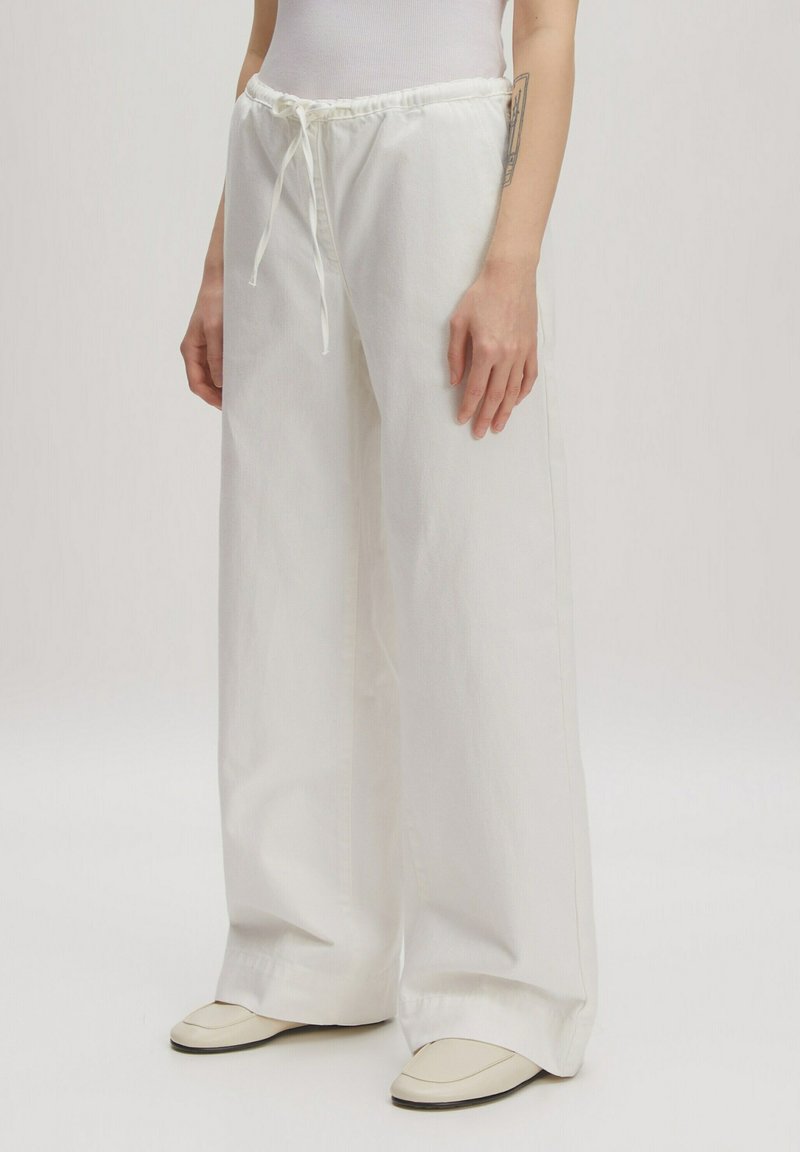 Witte wijde broek met elastische tailleband en verstelbaar koord. Gemaakt van zachte stof, met een gladde, gestructureerde afwerking.
