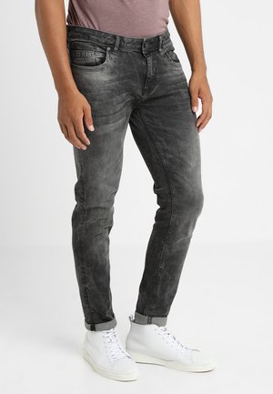 Zwarte denim jeans met een vervaagde afwerking, voorzien van een slim fit, zakken en stiksel details. Combinatie met witte high-top sneakers.