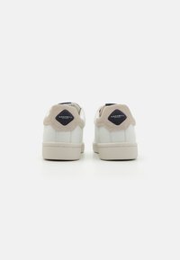 Vita lädersneakers med beige mockadetaljer, rund tå, platt gummisula och logotypdetalj på hälfliken.