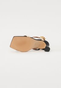 Sorte og beige høyhælte sandaler med firkantet tådesign, smale stropper og en teksturert såle med en stabil blokkhæl.