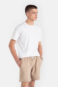 Biała bawełniana koszulka z krótkim rękawem w połączeniu z beżowymi szortami na sznurku. Tkanina jest gładka, z luźnym krojem i minimalistycznym wzornictwem.