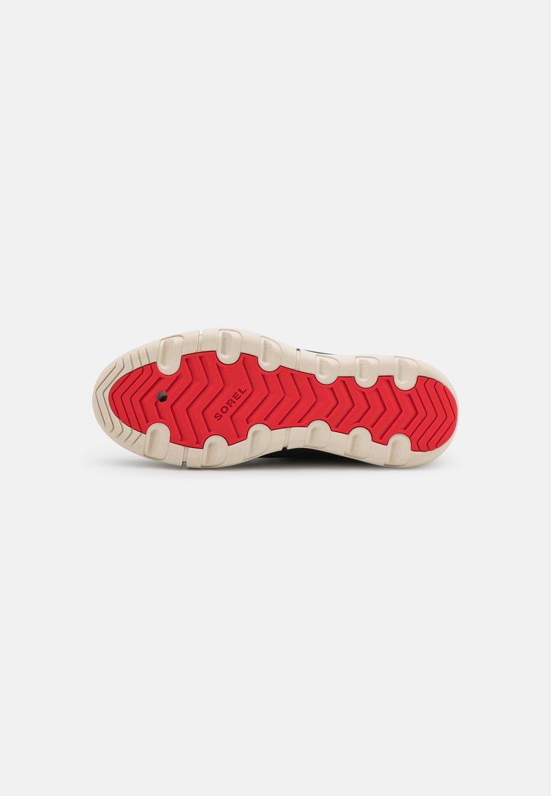Soletta della scarpa con un motivo ondulato rosso, in materiale gomma, con caratteristiche di trazione integrate e una base bianca. Il marchio "SOREL" è visibile.