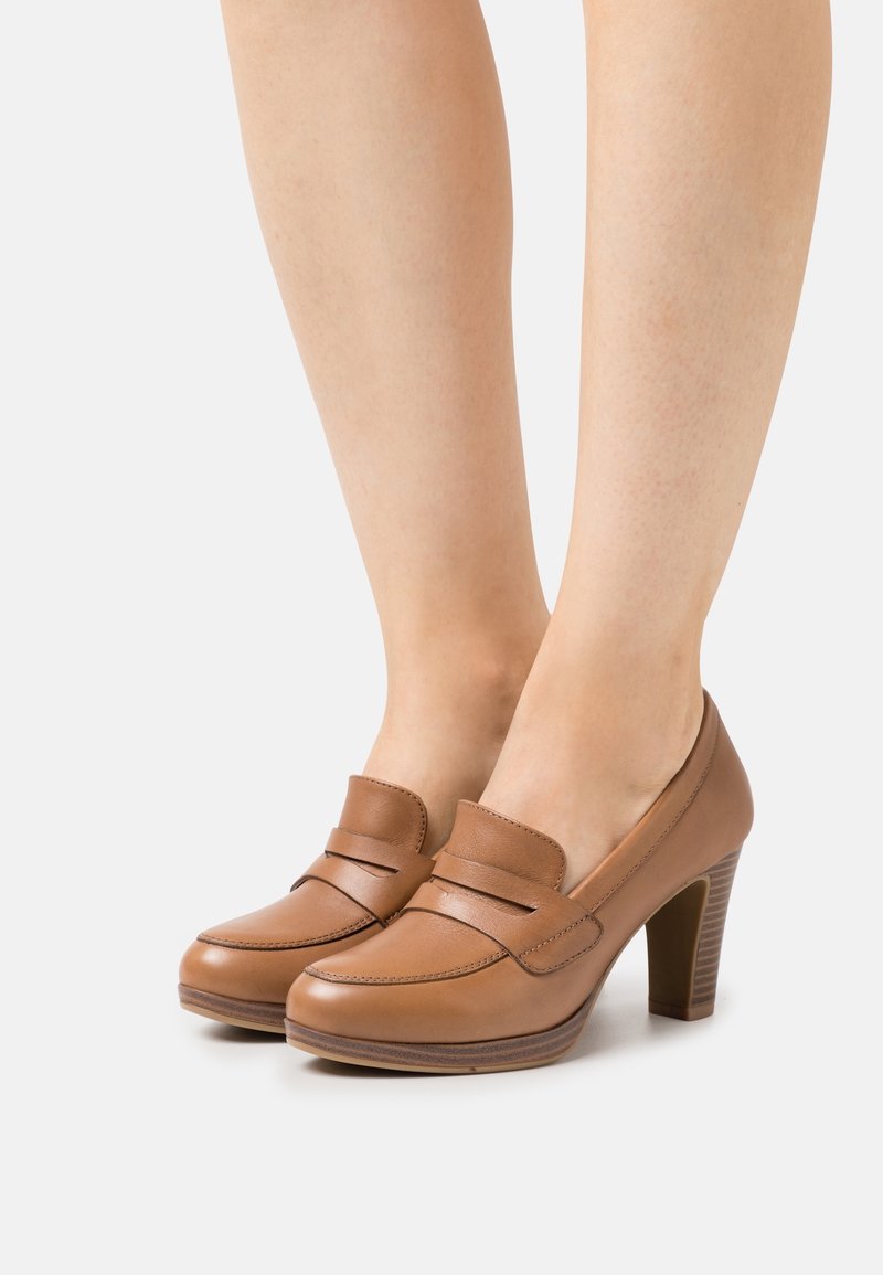 Mocassins à talons hauts en cuir marron avec une finition lisse, dotés d'une sangle d'accent cousue sur le devant et d'un talon bloc texturé.