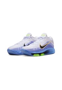 Lichte sportschoenen met een wit en blauw gebreid bovenwerk, zwarte Nike swoosh en groene accenten op de zool voor demping.