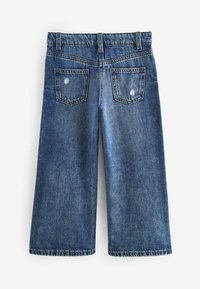Shorts culotte in denim di un blu medio con finitura sbiadita. Presenta due tasche posteriori, dettagli sfrangiati e un design a gamba larga.