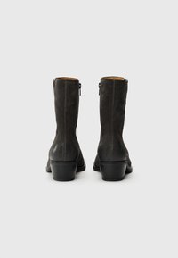 Stivaletti alla caviglia in suede nero con finitura liscia, tacco a blocco di altezza media e chiusura con zip sul retro. Design semplice ed elegante.
