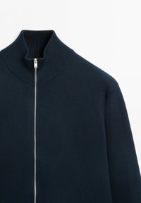 Mörkblå zip-up tröja med ribbad hög krage, visad mot en vit bakgrund.