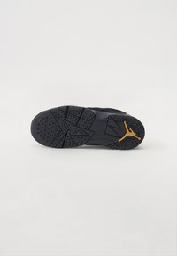 Melnas sporta apavu zoles ar teksturētu rakstu, kas satur apļus un zvaigžņu formas, papildināta ar zelta Jumpman logo.