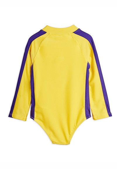 Κίτρινο κορμάκι με μακριά μανίκια και μοβ ρίγες κατά μήκος των μανικιών και των πλευρών, με ψηλό γιακά και σχεδιασμό ραγκλάν.