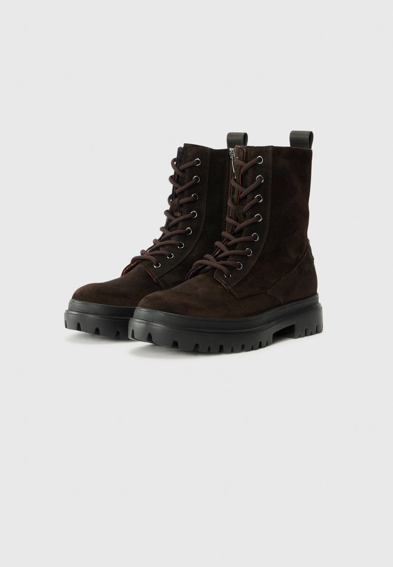 Braune Wildleder-Schnürstiefel mit einer robusten schwarzen Gummisohle, runder Zehenform und Zuglasche für ein einfaches Anziehen, entworfen für Haltbarkeit und Griffigkeit.