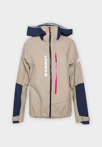 Chaqueta de exterior beige con detalles en azul marino, que incluye un bolsillo con cremallera rosa y un cuello alto. Fabricada con material resistente a las inclemencias del tiempo y con un corte holgado.