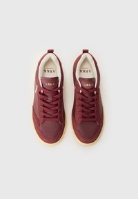Pair of maroon ARKK Copenhagen sneakers with beige interior lining and gum soles, shown from above on a white background.