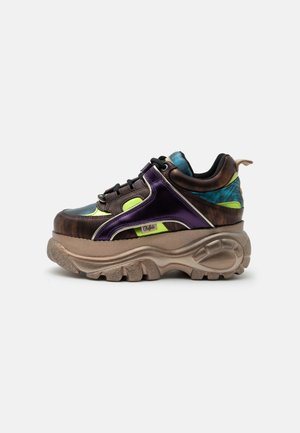 Sneaker chunky con suola beige spessa, tomaia metallizzata viola e marrone, dettagli verde neon, lacci neri e collarino del tallone blu a fantasia.