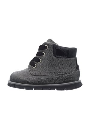 Grauer Kleinkinderstiefel mit schwarzen Schnürsenkeln, glänzendem schwarzen Schaftabschluss und dicker schwarzer Sohle, von der Seite auf weißem Hintergrund gezeigt.