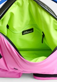 Rosa Tasche mit glatter Oberfläche, ausgestattet mit einem leuchtend grünen Innenfutter, Reißverschlusstasche und einem schwarzen Markenetikett.