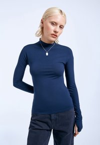 Marineblaues Langarmoberteil mit hohem Kragen und enganliegendem Design. Hergestellt aus glattem, dehnbarem Stoff mit Daumenlöchern an den Ärmelenden.