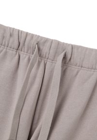 Lichtgrijze katoenen sweats met een elastische tailleband, twee trekkoorden en platte naden, die een zachte textuur en rekbaar materiaal tonen.