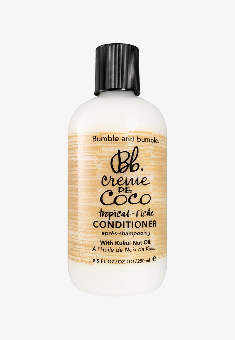 Bouteille en plastique blanche avec un bouchon noir strié. Présente un texte beige sur un fond clair. Étiquetée "Bumble and Bumble crème de Coco CONDITIONNEUR."
