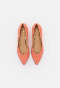 Escarpins corail à bout pointu en tissu lisse avec un devant échancré, dotés d'une semelle intérieure beige et d'un branding discret à l'intérieur.