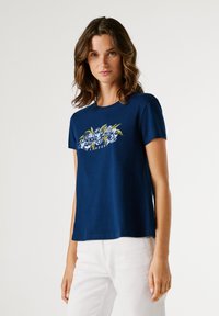 Μπλε-ναυτικό βαμβακερό μπλουζάκι με κοντά μανίκια και στρογγυλή λαιμόκοψη, με φυτικό γραφικό σχέδιο σε πράσινο και μπλε στην περιοχή του στήθους.