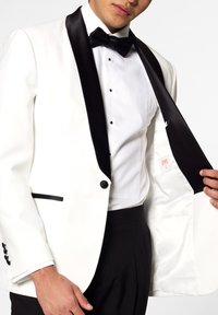 White tuxedo jacket with black satin lapels, single button closure, and black pocket accents; worn over a white dress shirt and black trousers.
