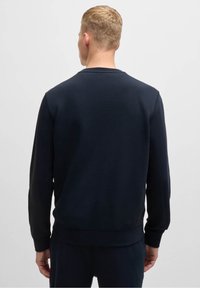 Námořnicky modrá mikina s kulatým výstřihem, žebrovanými manžetami a lemem v pase. Vyrobena z měkké látky s hladkým povrchem a minimálním množstvím značkových prvků.