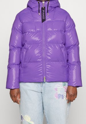 Lila glänzende Steppjacke mit Kapuze und Frontreißverschluss, kombiniert mit hellblauen Jeans mit bunten Patchwork-Blumendesigns.