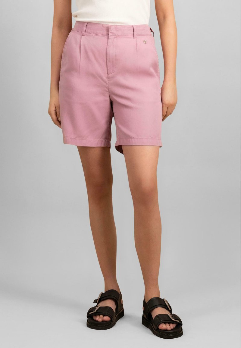 Rosa bomullsshorts med skreddersydd design, med frontfolder og sidelommer. Brukt med svarte sandaler.