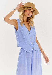 Svetlomodré ľanové šaty bez rukávov s V-výstrihom, gombíkovými detailami a rozšírenou sukňou. Obsahujú bočné vrecká a štruktúrovaný povrch.