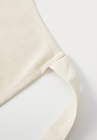 Kraftstoffrem av bomull i off-white, med en teksturert overflate og pent stiching, med en glatt, buet kant for komfort.
