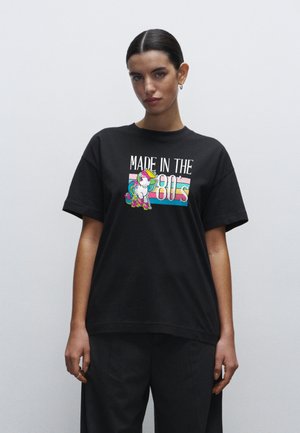 Sort bomulds t-shirt med teksten "MADE IN THE 80's" og en farverig unicorn grafik. Rund hals og afslappet pasform med korte ærmer.