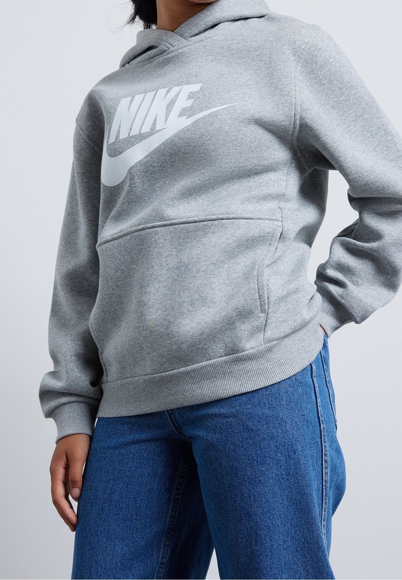 Grå Nike hoodie med en stor vit logga, tillverkad av mjukt material, med en känguruficka, ribbad mudd och huva med dragsko.