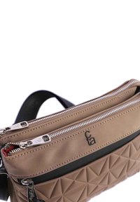 Bolso cruzado bicolor en beige y negro, con un patrón de diamantes texturizados, dos cremalleras plateadas y un detalle del logo en la parte frontal.