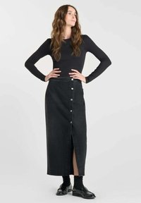 Zwarte denim maxi rok met een sluiting aan de voorkant en een split aan de zijkant. Gekocht met een aansluitend lange mouwen top en zwarte instappers.