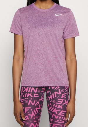 Femme portant un t-shirt Nike violet chiné et des leggings noirs avec des motifs de logo Nike rose vif.
